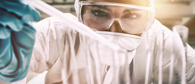 lab worker in protective glasses looking intensely at pipette