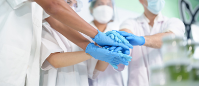 lab scientists working together with hands together in blue gloves